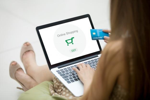 Mulher com um cartão de crédito e um computador portátil