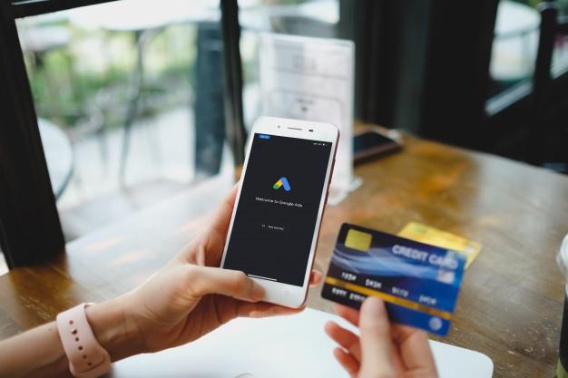 Mulher está digitando no google ads e cartão de crédito a partir de um telefone celular.